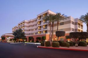 un bâtiment avec des palmiers et des buissons devant lui dans l'établissement Courtyard by Marriott Scottsdale Old Town, à Scottsdale