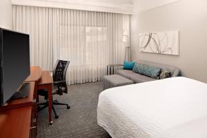 a hotel room with a bed a desk and a tv at Courtyard by Marriott Houston Rice University in Houston
