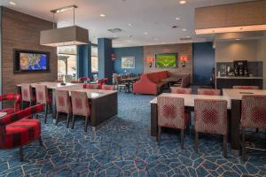 a restaurant with red chairs and tables and a bar at TownePlace Suites by Marriott Altoona in Altoona