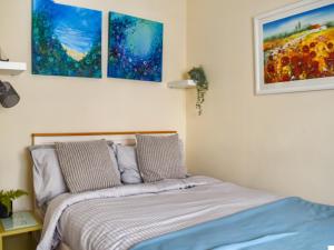 a bed in a bedroom with three paintings on the wall at The Old Sail Loft in Torquay