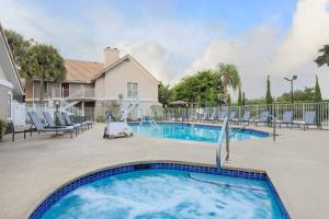 a swimming pool in a yard with chairs and a house at Residence Inn Boca Raton in Boca Raton