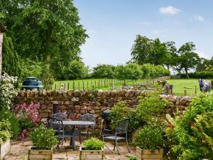 um jardim com mesas e cadeiras e uma parede de pedra em Mere Croft em Sebergham