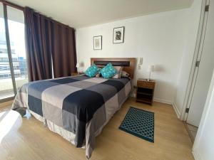 - une chambre avec un grand lit et des oreillers bleus dans l'établissement Agradable departamento, frente a la Quinta Vergara, à Viña del Mar