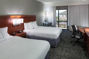 a hotel room with two beds and a desk at Courtyard by Marriott Santa Clarita Valencia in Valencia
