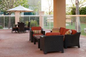 a patio with chairs and a table and an umbrella at Courtyard by Marriott Santa Clarita Valencia in Valencia