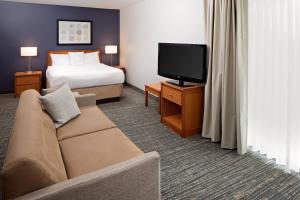 um quarto de hotel com uma cama, um sofá e uma televisão em Residence Inn Lexington North em Lexington