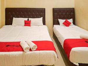a bedroom with two beds with red and white sheets at RedDoorz Syariah At Harley Hotel Sabang in Sabong