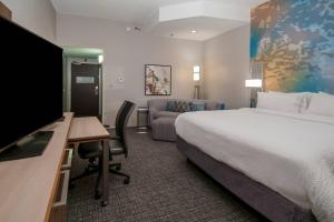 a hotel room with a bed and a desk with a television at Courtyard by Marriott Bentonville in Bentonville