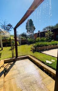 een patio met uitzicht op een tuin en een bank bij Aconchego na montanha com BANHEIRA de imersão e 5 suítes 7,5km do centro Águas de Lindóia in Águas de Lindóia