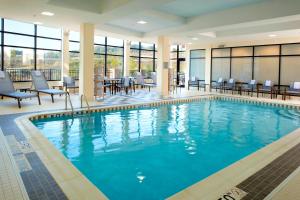 a pool in a hotel with chairs and tables at Courtyard Pittsburgh Settlers Ridge/Robinson Township in Robinson Township