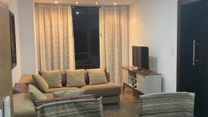 - un salon avec un canapé et une télévision dans l'établissement Punta Centinela Apartment, à Punta Blanca