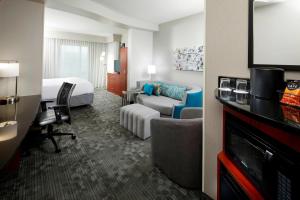 a hotel room with a bedroom and a bed and a tv at Courtyard Pittsburgh Settlers Ridge/Robinson Township in Robinson Township