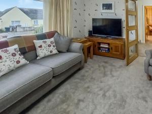uma sala de estar com um sofá e uma televisão de ecrã plano em The Shieling em Biggar