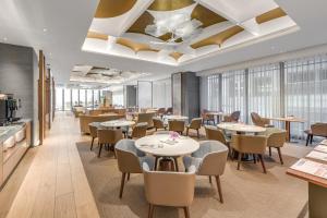a restaurant with tables and chairs and windows at DoubleTree by Hilton Taipei Zhongshan in Taipei