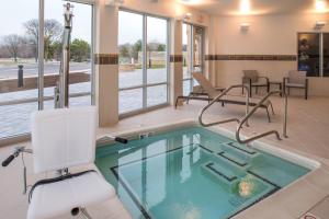 a pool in a room with chairs and a table at Courtyard by Marriott Detroit Farmington in Farmington Hills