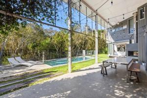 une terrasse intérieure avec une table et une piscine dans l'établissement 25 Whitehaven Parade, à Yaroomba