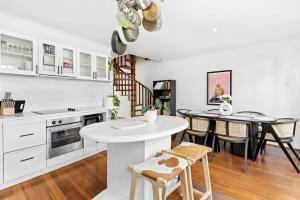 a kitchen with white cabinets and a table and chairs at 5 North Freo 2br Supercool Pad & Parking in North Fremantle