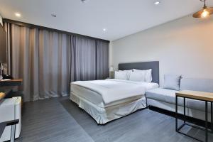 sypialnia z dużym białym łóżkiem i kanapą w obiekcie The First Hotel w mieście Changwon