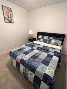 een slaapkamer met een blauwe en witte quilt op een bed bij Basement suite in Winnipeg
