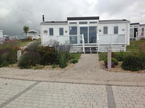 a white tiny house in a yard with flowers at Ritz Summerhouse in Hastings