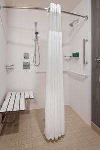 a white shower curtain in a bathroom with a bench at Courtyard Philadelphia Willow Grove in Willow Grove