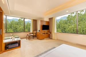 a bedroom with large windows and a television at The Prominence Mussoorie Road Dehradun in Dehradun