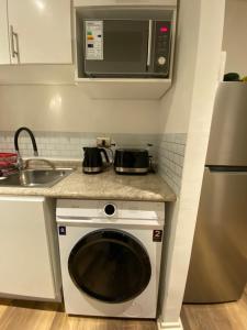 eine Küche mit einer Mikrowelle und einer Waschmaschine in der Unterkunft Arriendo Departamento con 2 habitaciones 1 baño en Concepción cerca de Aeropuerto in Concepción