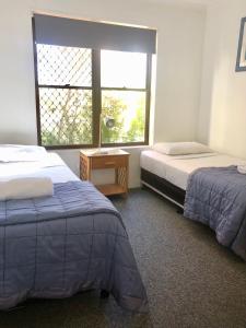 a room with two beds and a window and a table at Kalua Holiday Apartments in Maroochydore