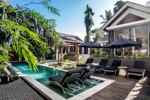 - une piscine avec des chaises et des parasols à côté d'une maison dans l'établissement Villa Dream by BaliSuperHost, à Ubud