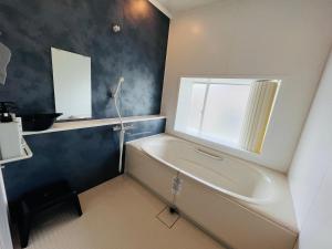 a bathroom with a bath tub and a window at HOSTEL OE in Yoshinogawa