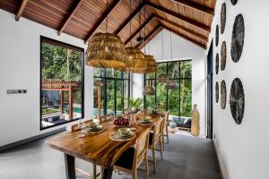 une salle à manger avec une grande table et des chaises en bois dans l'établissement Villa Dream by BaliSuperHost, à Ubud
