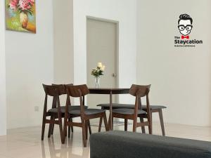 a table with four chairs and a vase with flowers at Staycation Homestay 5 Hills 68 Apt Near Imperial in Kuching