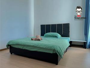 a bedroom with a bed with a green comforter at Staycation Homestay 5 Hills 68 Apt Near Imperial in Kuching