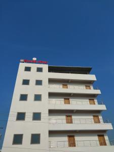 a tall white building with a red sign on it at LK GRAND HOME in Tirupati