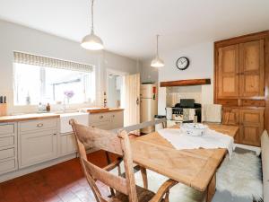 a kitchen with a wooden table and a kitchen with a stove at Lucky Cottage in Foxt