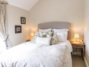 a bedroom with a large white bed with pillows at Lucky Cottage in Foxt