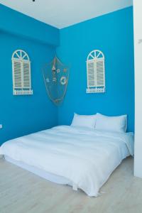 a blue bedroom with a white bed and two windows at Love Green in Green Island