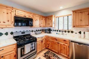eine Küche mit Holzschränken und einem Herd mit Backofen in der Unterkunft Alameda Landing- Pool Table- Hot Tub- Relaxing Log Cabin in Big Bear Lake