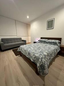 een slaapkamer met een bed en een bank bij Lujosa Suite piso 19 La Carolina in Quito