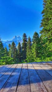 a wooden deck with trees and mountains in the background at Echoes of the mountains in Mestia