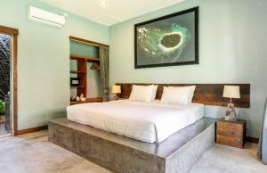 Un dormitorio con una gran cama blanca con un banco alrededor. en Big Brother Surf Inn, en Canggu 37 fotos más