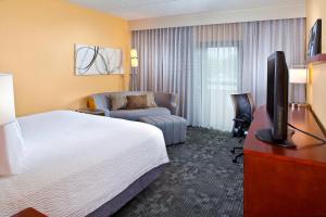 um quarto de hotel com uma cama, uma televisão e um sofá em Courtyard Miami Airport West/Doral em Miami