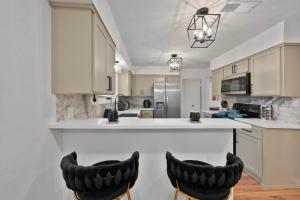a kitchen with two black chairs at a counter at Green Resort: 3bd/2.5 bath near AT&T Stadium in Arlington