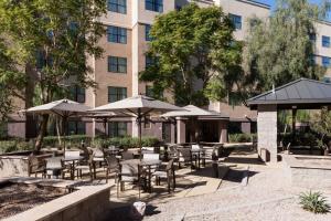 a patio with tables and umbrellas in front of a building at Residence Inn Phoenix North Happy Valley in Phoenix