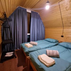 two beds in a wooden room with purple curtains at Hooni_guesthouse in Odzun