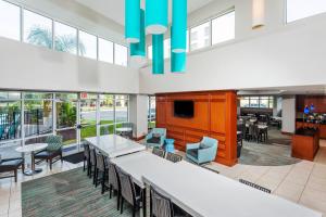 eine große Lobby mit Tischen, Stühlen und Fenstern in der Unterkunft Residence Inn Orlando Airport in Orlando