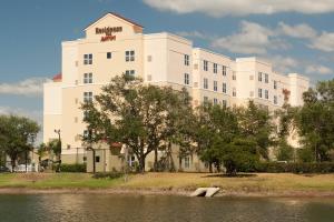 a large white building next to a body of water at Residence Inn Orlando Airport in Orlando