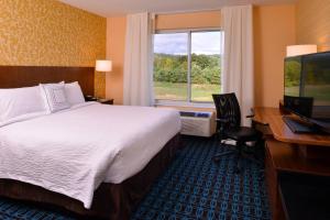Fairfield Inn & Suites by Marriott Plymouth White Mountains في بليموث: غرفه فندقيه بسرير ومكتب ونافذه
