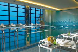 a swimming pool with two tables and chairs next to it at Ambassador Hotel Hsinchu in Hsinchu City