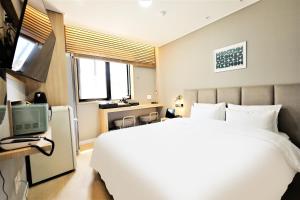 a bedroom with a large white bed and a television at De Lamour Hotel in Tongyeong